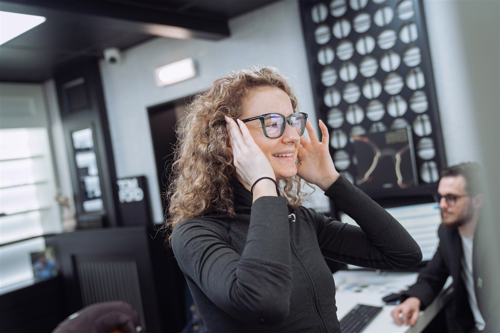 A patient trying on frames in our boutique, with our optometrist behind her